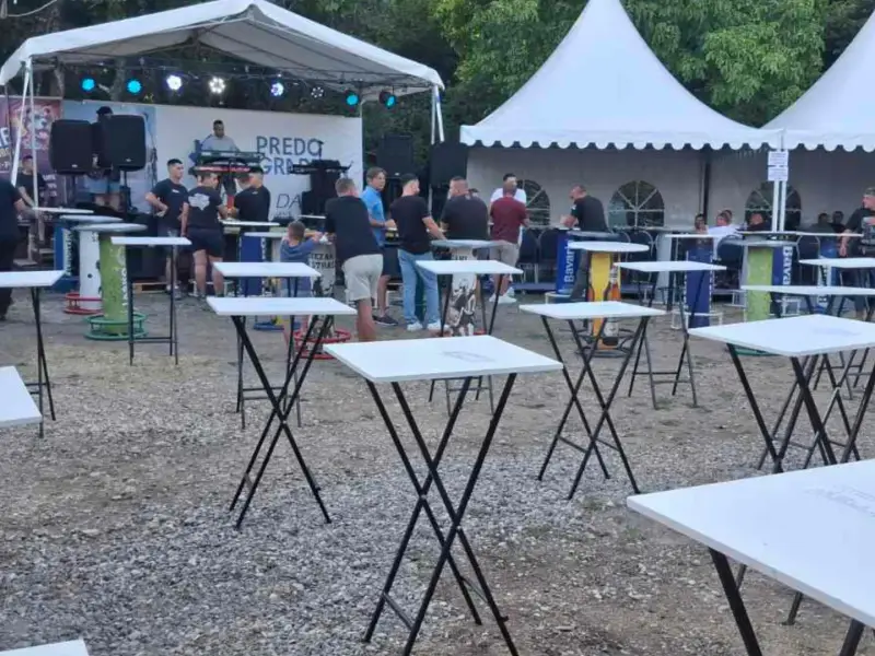 Sklopivi barski stolovi na događaju na otvorenom, u pozadini bina i šatori